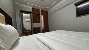 A bedroom with a bed, a wardrobe, and a mirror. - The Capstone (New Delhi)