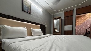 A neatly made bed with white linens in a hotel room. - The Capstone (New Delhi)