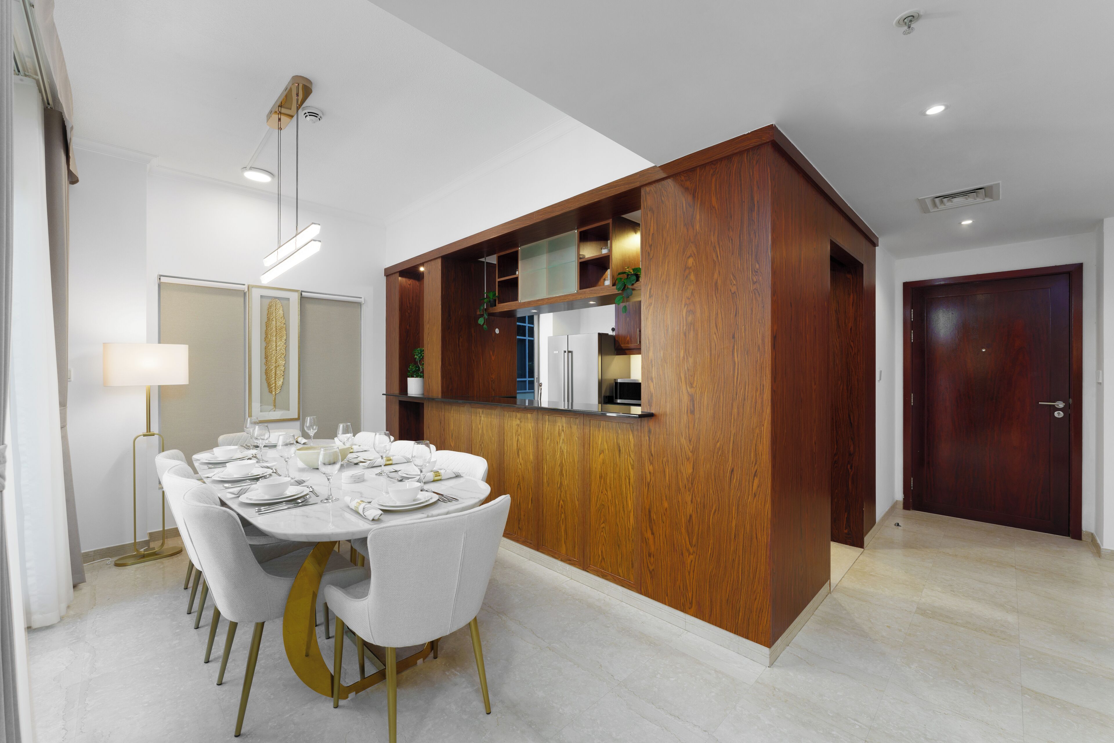 Un espace repas moderne avec une table blanche dressée pour six personnes, entourée de chaises blanches aux pieds dorés.