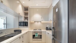 A modern kitchen with stainless steel appliances, white cabinetry, and a built-in oven. - Luxury Living Spectacular Burj Views (Dubai)