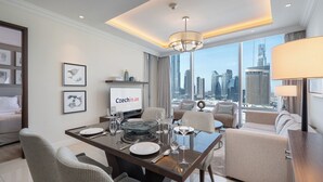 A modern hotel room with a dining area, a sofa set, and a city view. - Luxury Living Spectacular Burj Views (Dubai)