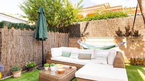 A cozy outdoor seating area with a wicker sofa, a small table, and a hammock. - Villa in Palma de Mallorca  (Palma)