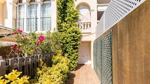 A narrow outdoor corridor with a tiled floor, surrounded by lush greenery and flowering plants. - Villa in Palma de Mallorca  (Palma)