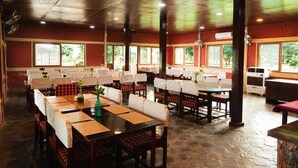 Un restaurante espacioso con varias mesas y cabinas, ventanas amplias y paredes de ladrillo.