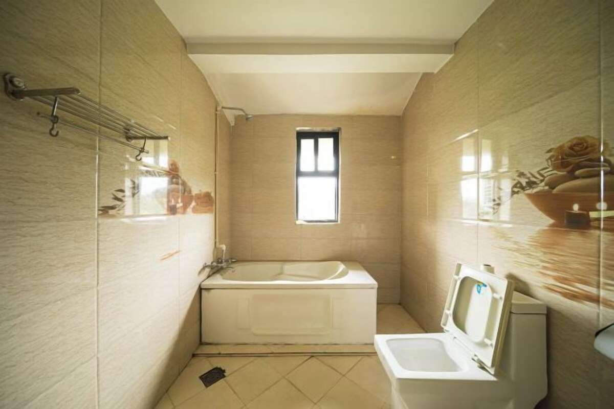 A bathroom with a bathtub, a toilet, and a window.