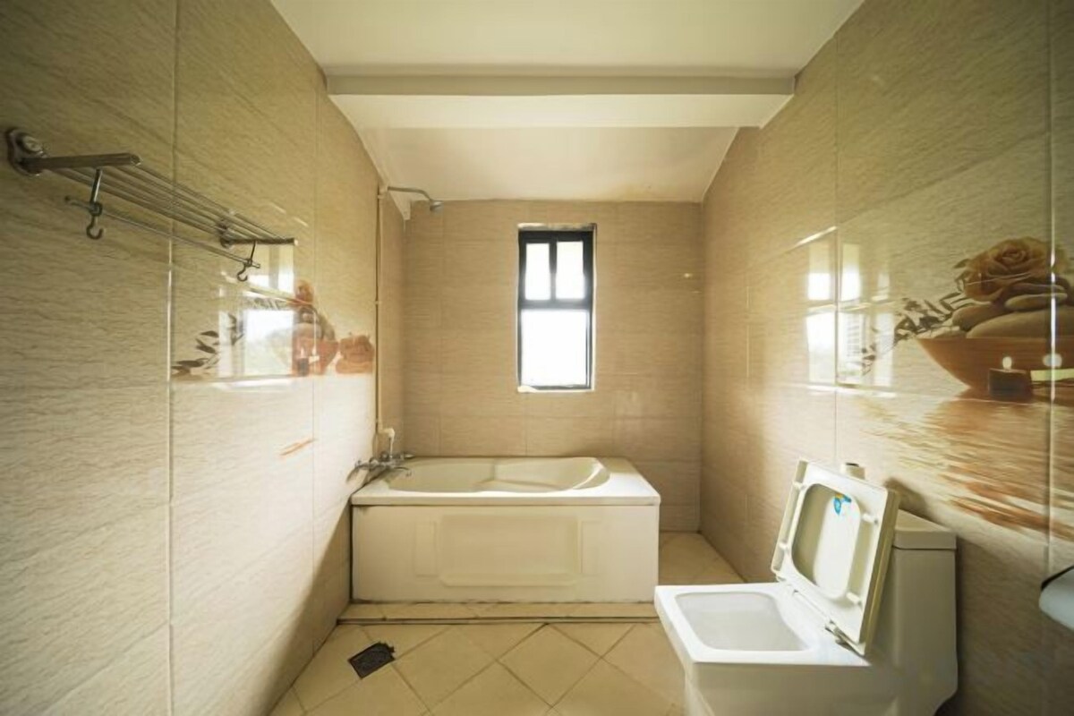 A bathroom with a bathtub, a toilet, and a window.