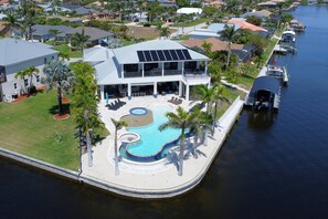 A waterfront property with a swimming pool, solar panels, and a dock.