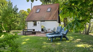 Une maison avec un toit en tuiles, une terrasse avec une table et des chaises, et une pelouse.