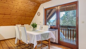 A dining area with a table set for four, wooden ceiling, and a view through a glass door. - Apartment Lavendel with Mountain View, Shared Terrace and No Wi-Fi (Kirchzarten)