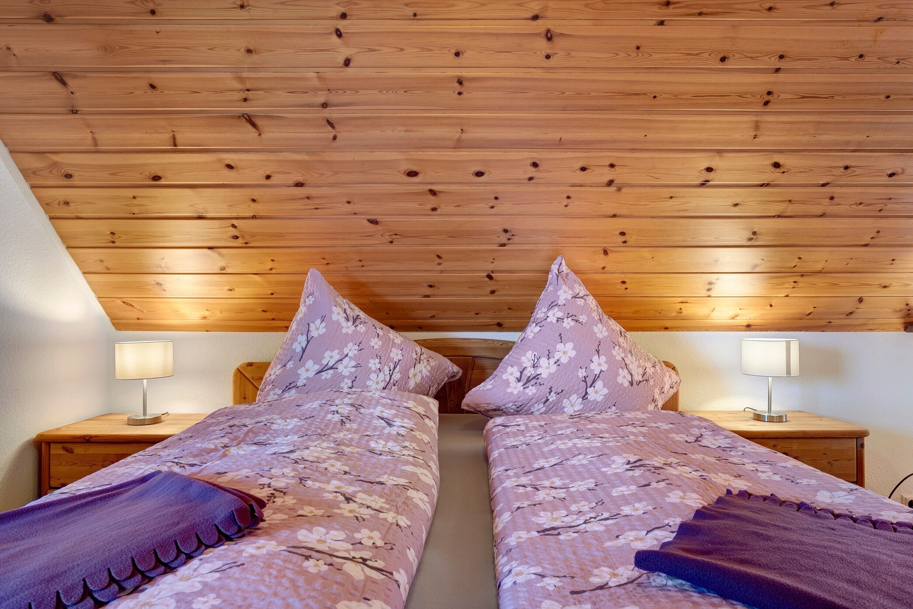 Une chambre avec deux lits, un plafond en bois et des tables de chevet avec des lampes.