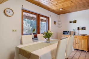 Un espace repas comprenant une table, des chaises, une horloge et une vue par la fenêtre.