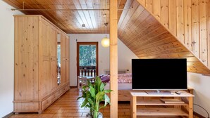 A wooden interior with a TV on a wooden stand, a plant, and a view of the outdoors. - Apartment Lavendel with Mountain View, Shared Terrace and No Wi-Fi (Kirchzarten)
