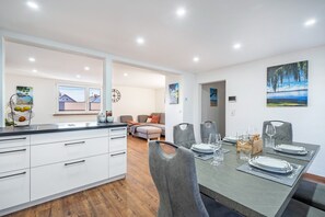 Una cocina moderna con armarios blancos y un comedor con una mesa dispuesta para cuatro.