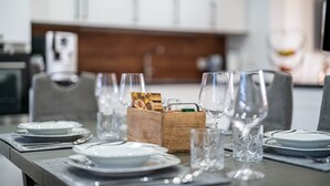 Una mesa de comedor dispuesta con platos, vasos y una caja de madera con cartas.