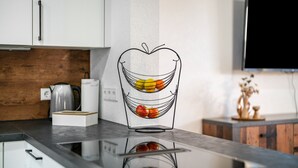 Una cocina de diseño moderno con encimera, hervidor y frutero.