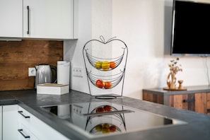 Una cocina de diseño moderno con encimera, hervidor y frutero.