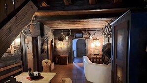 A rustic interior with wooden walls, antler decorations, a wooden table, and a bench.