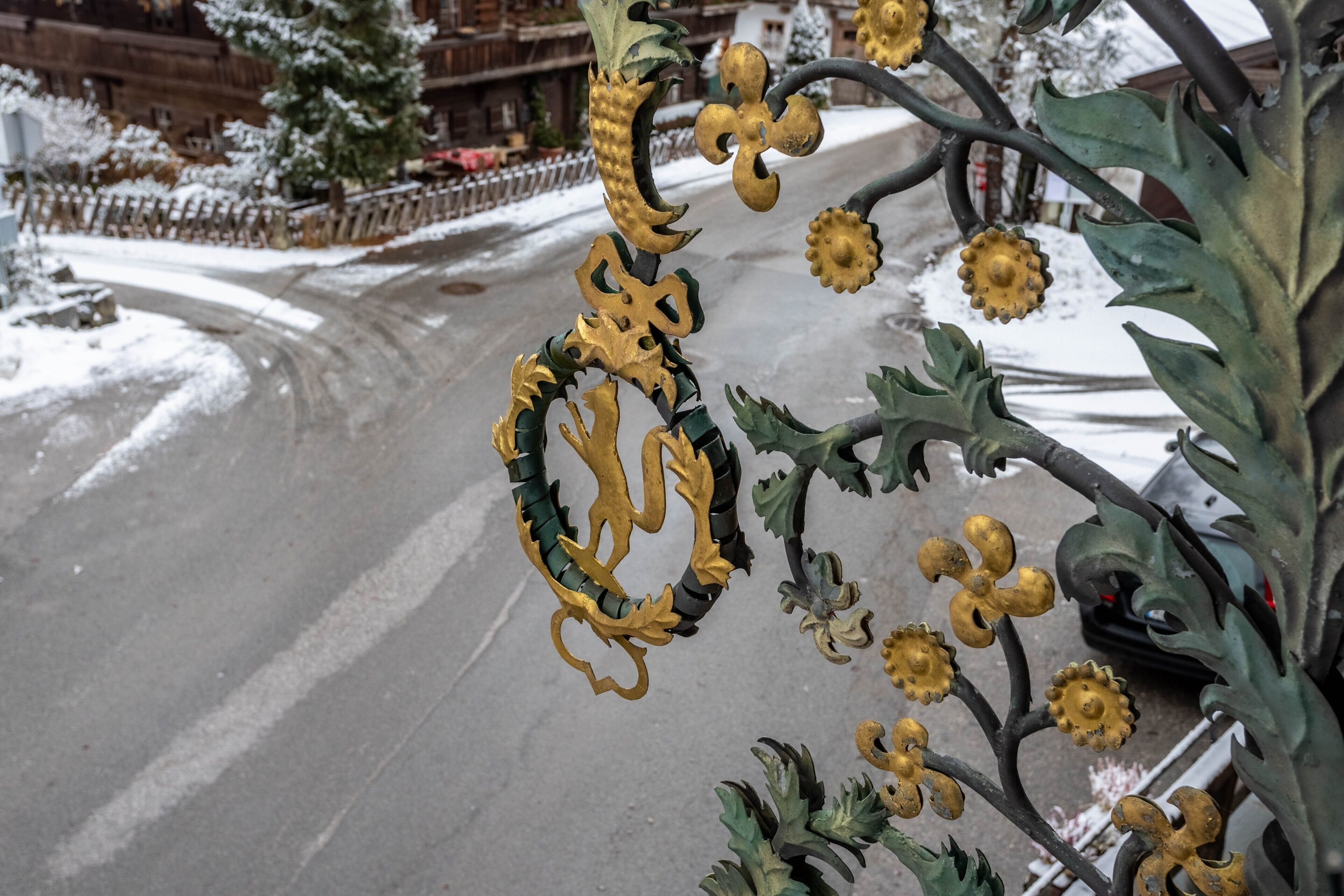Una valla de metal con diseños intrincados y nieve en el suelo.