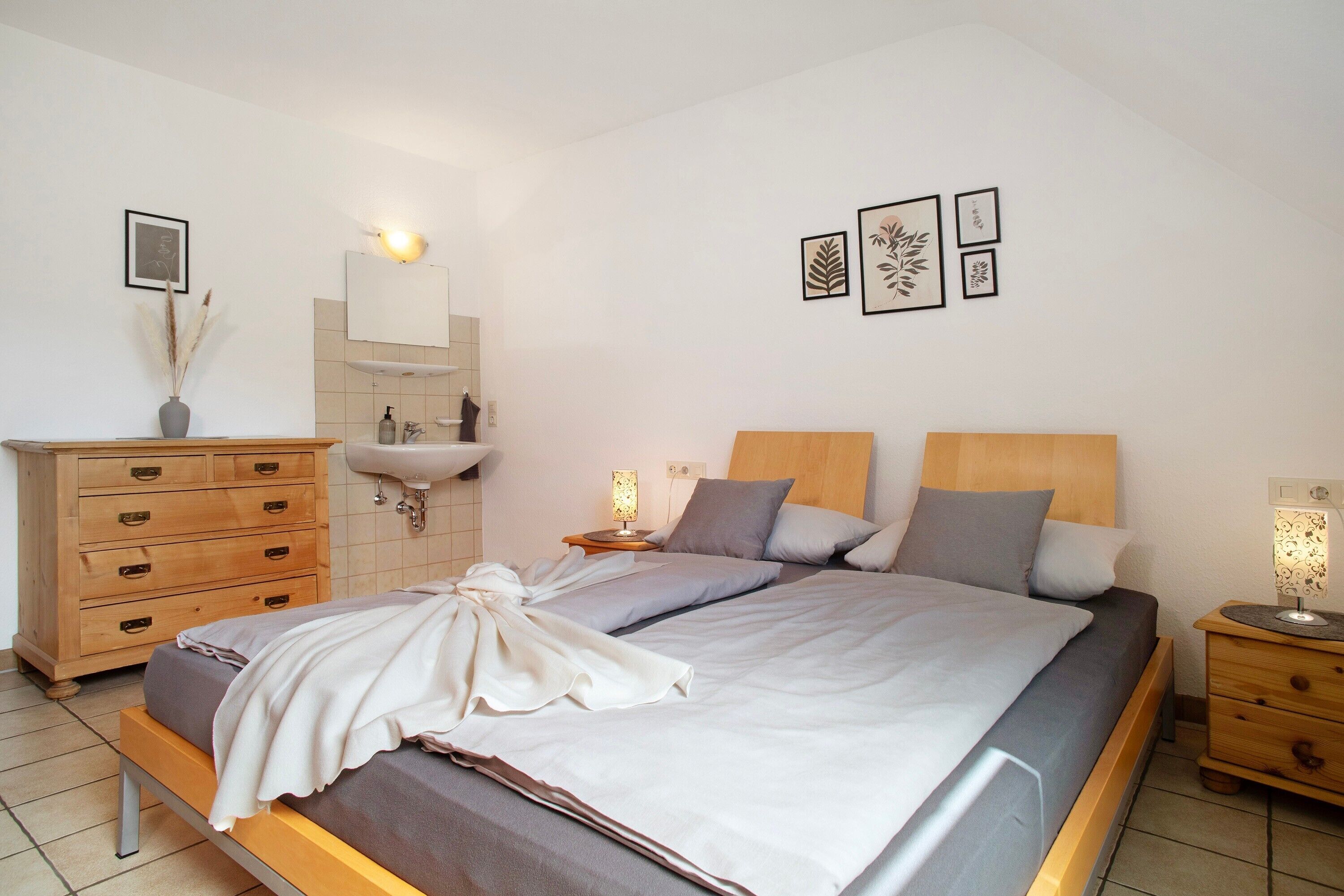 Una camera da letto con un letto, una cassettiera in legno, un comodino, una lampada e uno specchio a parete.