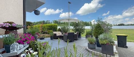 An outdoor patio with seating, potted plants, and a view of a lake.