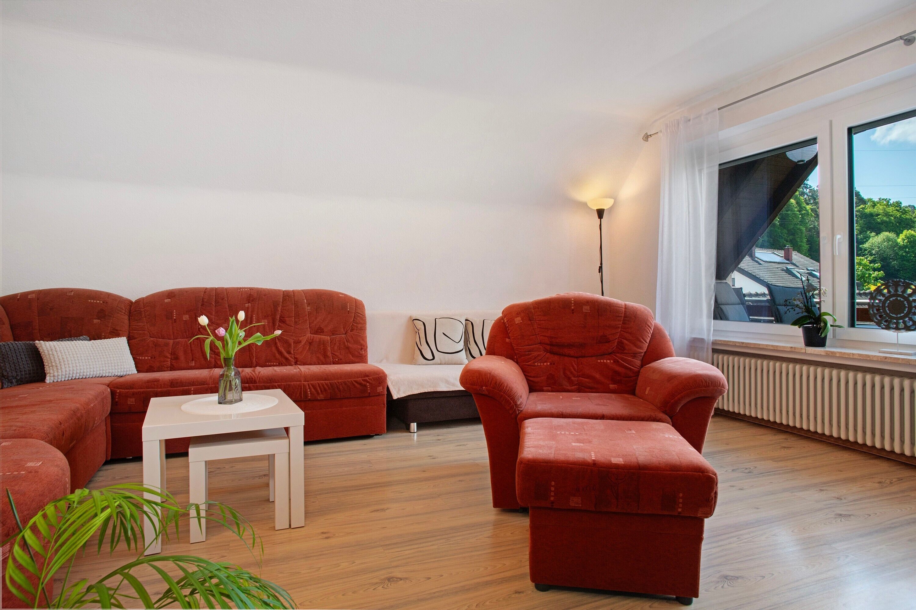 A living room with a sectional sofa, a single armchair, a small table, and a floor lamp.