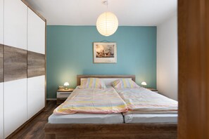 Une chambre à coucher avec un lit, des tables de chevet, un luminaire suspendu et un tableau encadré au mur.