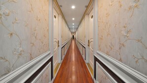 A long, narrow hallway with ornate floral wallpaper on both sides and a wooden floor. - Halong Aquarmarine Royal Cruise  (Tuan Chau)