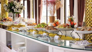 A buffet with various dishes and a decorative vase of flowers. - Halong Aquarmarine Royal Cruise  (Tuan Chau)