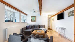 A modern living room with a sectional sofa, a coffee table, and a television mounted on the wall.