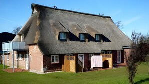 A thatched-roof house with a brick exterior, a wooden door, and a small garden.