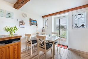 Un comedor con sillas de madera, una mesa blanca y una cocina con lavavajillas.