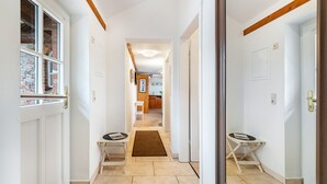 A hallway with a door on the left, a small table with a magazine, and a door on the right.
