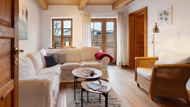 Una sala de estar acogedora con un sofá blanco, un sillón de mimbre y una mesa de centro.