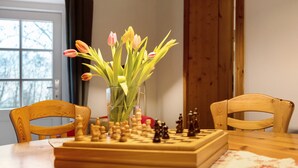 Un échiquier posé sur une table, avec un vase de tulipes en arrière-plan.