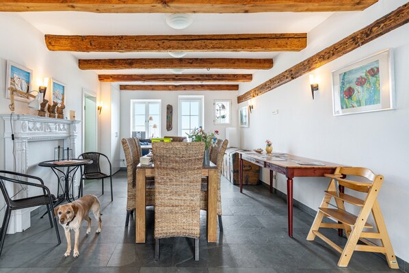 Un coin repas avec une table en bois, des chaises en osier, un chien et une cheminée.