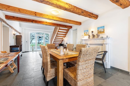 A dining area with a wooden table and wicker chairs, a fireplace, and a staircase.. Apartment 'Am Halbmond 2' with Private Terrace, Private Garden and Wi-Fi