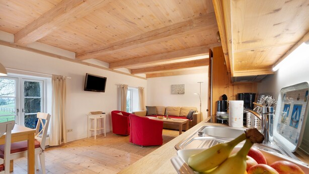 Un intérieur en bois comprenant un coin cuisine, une table à manger et une chaise rouge.