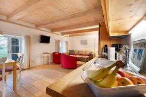 Un intérieur en bois comprenant un coin cuisine, une table à manger et une chaise rouge.