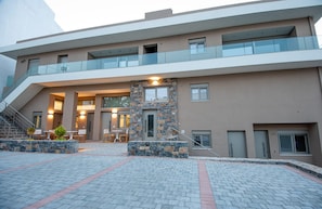 Un edificio moderno a più piani, con una scala centrale, un’area salotto all'aperto e un muro in pietra decorativo.