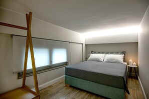 Una camera da letto con un letto, un comodino con una candela e una scala di legno appoggiata al muro.