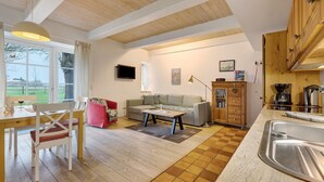 A modern living room with a sofa, dining table, and kitchen area.