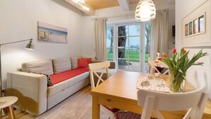 A cozy living area with a sofa, a dining table, and a view of the outdoors.