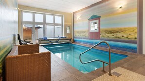 An indoor swimming pool with a view of a desert landscape through a large window.