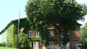 A two-story building with a brick facade, a large tree in front, and a well-maintained lawn.