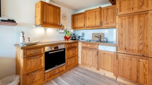 Una cocina con armarios de madera, estufa y pileta.