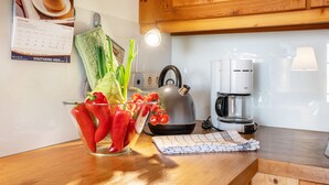 Una encimera de cocina con una tetera, una cafetera y un bol de vidrio con verduras.