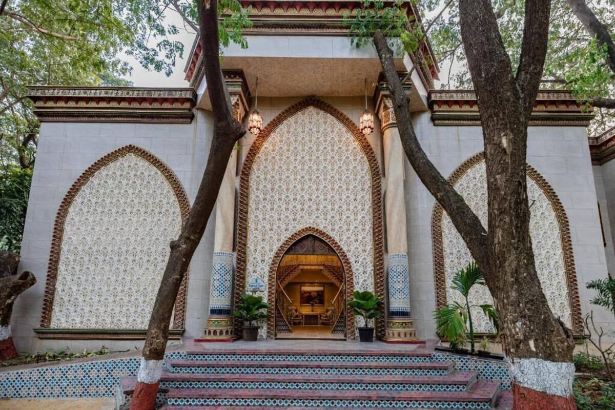 A building with ornate arches and patterned walls, featuring a central entrance with steps leading up to it.