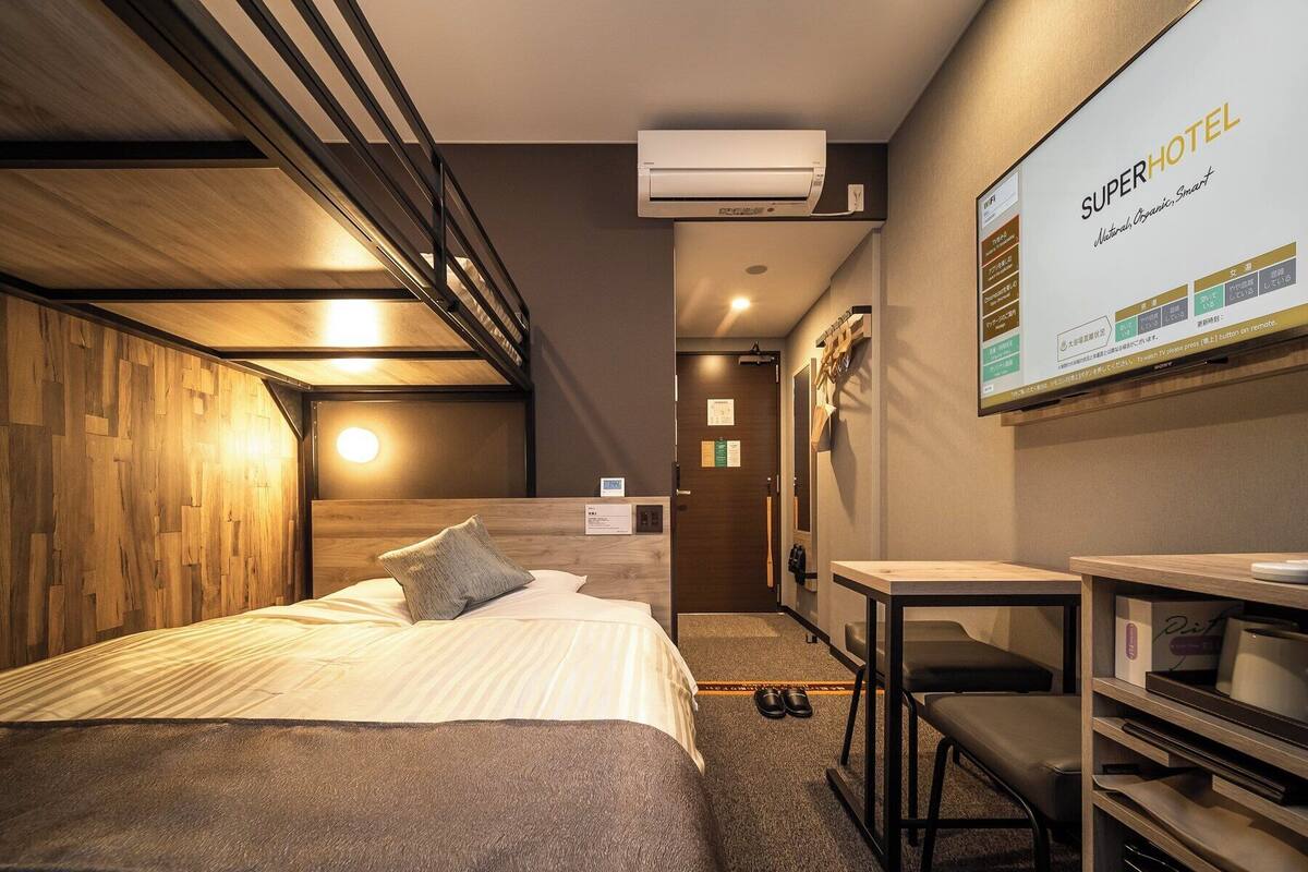 Habitació d'hotel amb un llit, un escriptori i una televisió penjada a la paret.