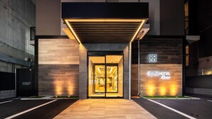 A hotel entrance with a modern design, featuring a glass door and illuminated signage. - Super Hotel Premier Namba Shinsaibashi Natural Hot Spring (Osaka)