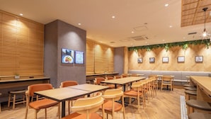A restaurant with wooden flooring, orange chairs, and tables. There are wall-mounted screens displaying menus. - Super Hotel Premier Namba Shinsaibashi Natural Hot Spring (Osaka)